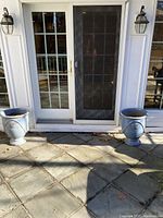Two large blue ceramic planters positioned outside, on patio in front of sliding glass door.