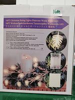 Photo of box label showing product details and branding for 16 ft pinecone shaped Christmas string lights with warm white LEDs, battery powered.