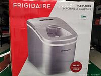 Boxed Frigidaire ice maker unit shown on product packaging with capacity and brand details visible.
