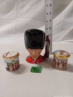 Royal Doulton Guardsman character jug with two enamel thimble containers, showing approximate size with ruler