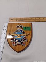 Front view of the wooden plaque with ruler for size reference showing the Royal Canadian Air Force crest with crown, eagle and motto.