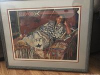 Framed art print showing a reclining woman on patterned textiles, signed and numbered by the artist.