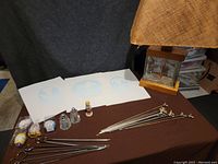 Photo showing all items on brown cloth including three embossed prints, vintage lamp, Hummel figurine, glass salt and pepper shakers, BBQ skewers and hand-painted eggs