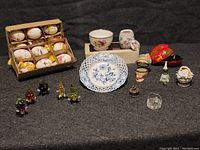 Wide view of all items, showing hand painted eggs in box, porcelain dishes, pill boxes, and glass fruit figurines