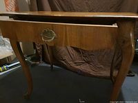 Side view of dressing table showing center drawer with decorative handle and curved legs.