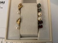 Overview of gold drop earrings on left and three pairs of studs on right in display box