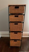 Front view of the tall storage tower showing all five wicker drawers in place within the metal frame.