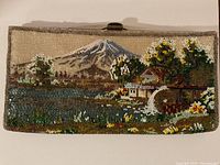 Full view of the vintage rectangular beaded clutch handbag with a detailed stitched landscape scene including a mountain, water, trees, and a watermill cottage.