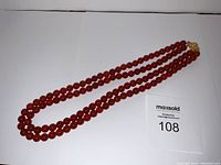 Full view of double-strand carnelian bead necklace laid flat