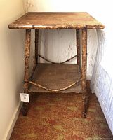 Front perspective showing bamboo frame, woven wicker top and lower shelf, and worn surfaces.