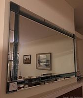 Front view of large beveled wall mirror with smoky blue detailing at edges, showing reflection of room interior.
