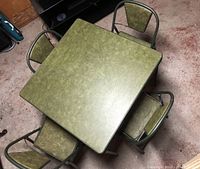 View from above showing the green Randall Durham card table top with four matching green vinyl chairs around it.