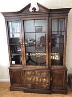 Frontal view of Drexel Heritage wood china cabinet showing glass doors, three drawers, and two closed cabinets.