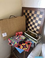 Photo showing all games and puzzle items: chess board, checkers, Peter Max Life Puzzle box, wooden box with mahjong pieces, and other boxed games.