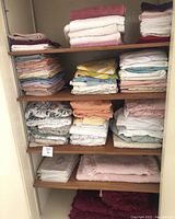 Shelves filled with folded linens including queen-sized sheet sets, bath towels, and bathroom shag set.