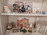 Shelf with vintage decorative items including clocks, artwork, vases, figurines, and child's decor