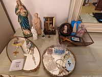 Overview of lot showing the variety of religious items displayed on mirror trays and in wire basket