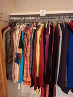 Closet rack with 20 women's clothing items including blouses, blazers, dresses in multiple colors and patterns.