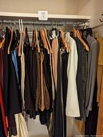 Hanging women's clothing, pants, skirts, and pantsuits in neutral colors including black, brown, beige, white, and grey.