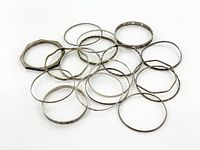 18 vintage sterling silver bangle bracelets laid out together showing varying shapes and designs including smooth, twisted, and stamped silver bangles.