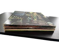 Side view showing 8 vintage vinyl record covers stacked, some edge wear visible.
