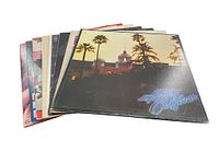Photo of all 8 vinyl records stacked with covers showing, including Hotel California as top album.