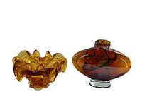 Amber coloured art glass vase and mid century modern ashtray placed side by side on white background showing shapes and color transparency.
