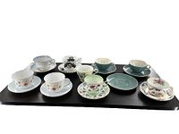 Full lot view showing all the assorted cup and saucer sets arranged on two trays.