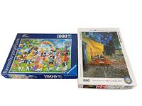 Two puzzle boxes side by side. Left is Ravensburger Disney 'Mickey's Birthday' 1000-piece puzzle with colorful cartoon characters and birthday scene. Right is Eurographics Fine Art Collection 'Cafe Terrace at Night' by Vincent van Gogh 1000-piece puzzle box showing art on the cover.