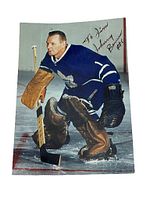 Full view of autographed photo showing Johnny Bower in Toronto Maple Leafs goalie uniform kneeling on ice with wooden hockey stick.
