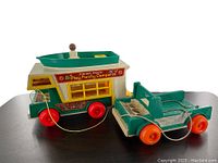 Side angle view of the Fisher Price Play Family Camper and its matching extra base, showing wheels, windows and boat on the roof.