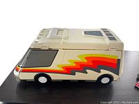 Side view of beige vintage Micro Machines camper van with colorful stripes and closed roof detail.