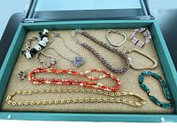 Wooden shadow display case containing a variety of costume jewelry pieces laid out inside