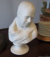 Front and side view of antique Parian ware bust showing the facial features, draped garment, and round pedestal base.