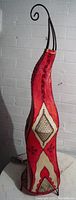 Side view of the red triangular cone floor lamp, showing the curved metal top and intricate pattern detail.