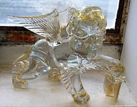 Full view of the transparent glass winged lion sculpture with gold accents showing the detailed wing, mane, and paws.