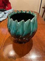 Front view of the artichoke-shaped vase showing detailed petal-like ridges and glossy green gradient glaze.