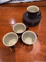 Four Denby espresso cups arranged to show the light green interior and dark matte exterior.