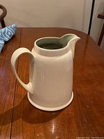 Full side view of the Denby pottery jug showing the beige exterior and handle.