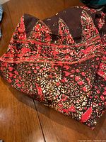 Photo showing the folded vintage batik fabric with clear red, black, and beige color and detailed patterns.