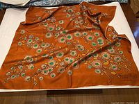 Full view of the square silk scarf laid flat, showing floral pattern and signature.