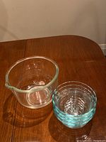 Overview of clear glass Sunbeam mixing bowl and smaller Pyrex glass bowls on wooden table