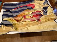 Vintage silk scarf signed by Claire MacDonald laid flat on table, showing its colorful abstract design and signature.