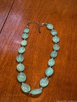 Photo of the full necklace laid out showing the fluorite beads in light green and amethyst beads in purple, with silver chain extension and clasp.