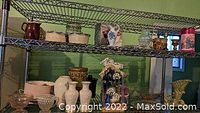 Two metal shelves displaying various Lenox ceramic and porcelain pieces, a Christmas manger sculpture centered on the second shelf, and multiple depression glass items including bowls and vases.