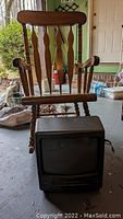Small vintage TV with built-in VCR placed in front of the wooden rocker chair, showing the screen and buttons.