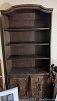 Full view of one bookcase showing three shelves and bottom two-door cabinet with carved details and handles