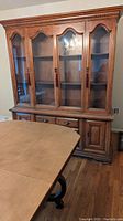 Front view of vintage solid wood china cabinet with glass display doors and lower drawers and cabinets.