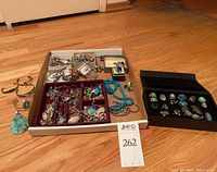 Overview of entire lot: cuffs, necklaces, red tray of mixed pendants, black box of rings