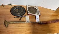Full view of lot showing giraffe brass brush and two brass sundials on wooden surface